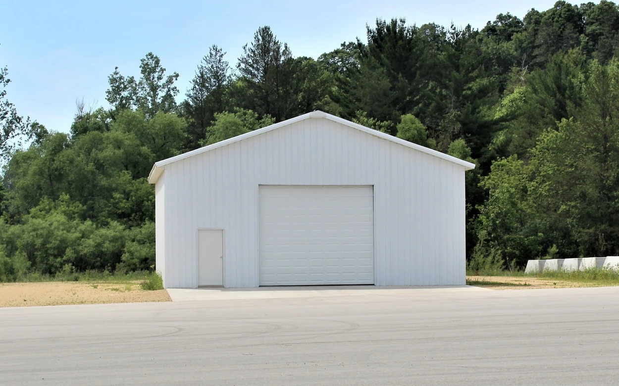 Reference photograph of a finished metal garage-style building with an overhead door and personnel entrance